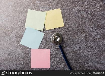 Above blank paper stick note list yellow, green, pink and blue with doctor stethoscope on concrete background, Health reminder concept