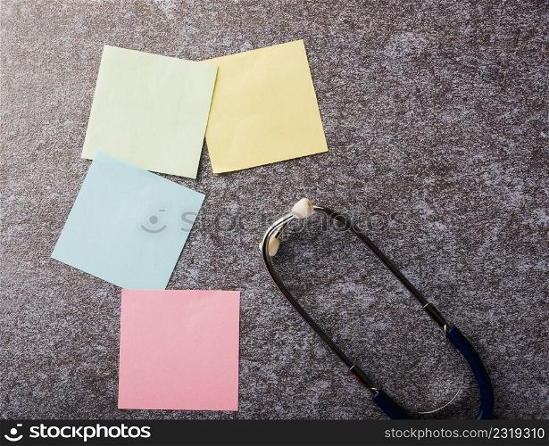 Above blank paper stick note list yellow, green, pink and blue with doctor stethoscope on concrete background, Health reminder concept