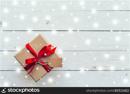 Above brown Gift box and red Ribbon, Snow with tag on white wood background with space.