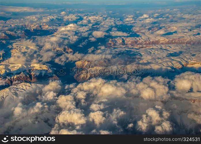 Above the clouds. The aerial view sees the landscape of mountains covered with ice and clouds floating over the mountains beautifully.