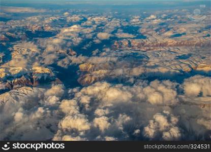 Above the clouds. The aerial view sees the landscape of mountains covered with ice and clouds floating over the mountains beautifully.