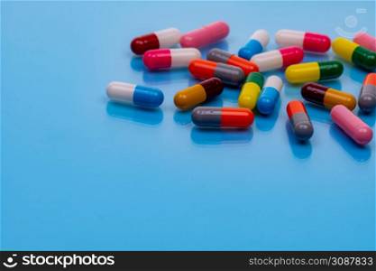 Above view colorful capsule pills on blue background. Prescription drugs. Pharmacology. Healthcare and medicine. Health budget and health policy. Many pills with space. Pharmaceutical industry.