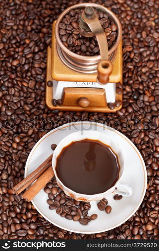 above view cup of coffee and roasted coffee beans with retro copper manual mill with cinnamon