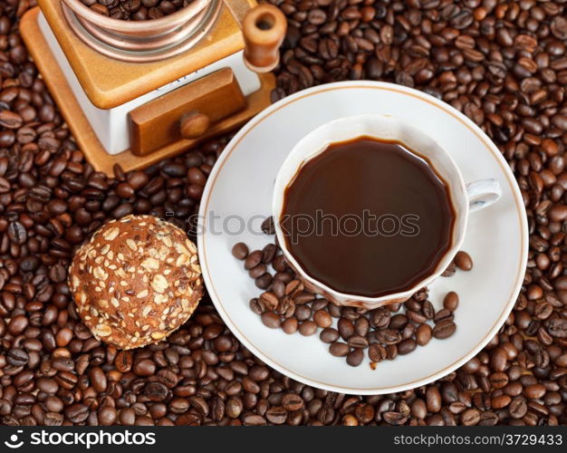 above view cup of coffee and roasted coffee beans with retro wood manual grinder with biscuit