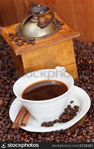 above view cup of coffee and roasted coffee beans with retro wooden manual mill, cinnamon close up