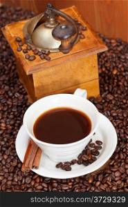 above view cup of coffee and roasted coffee beans with retro wooden manual mill, cinnamon
