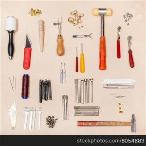 above view of collection various leathercrafting tools on natural leather surface