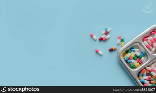 Above view of Colorful antibiotic capsule pills on a tray and blue background. Antibiotic drug resistance. Antimicrobial drugs. Prescription drugs. Pharmaceutical industry. Health care and medicine.