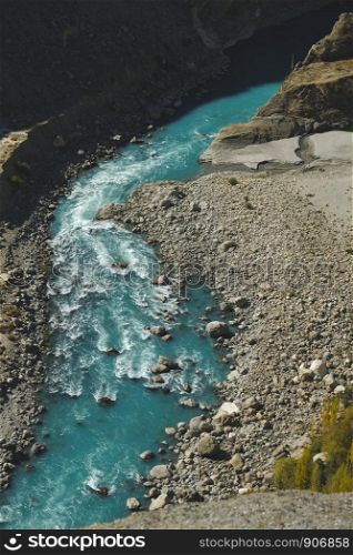 Above view of fresh water of winding turquoise blue river flowing through Karakoram mountain range. Gilgit Baltistan, Pakistan.