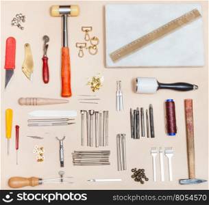 above view of set of various leatherwork tools and marble board on natural leather surface