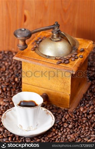 above view small cup of coffee and roasted coffee beans with retro wooden manual mill