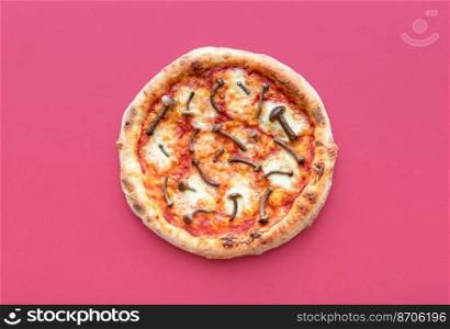 Above view with a freshly baked pizza minimalist on a dark pink table. Vegetarian pizza with wild edible mushrooms, tomato sauce, and mozzarella