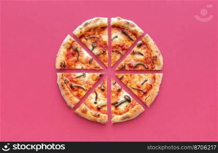 Above view with a sliced pizza isolated on a red-magenta table. Delicious homemade pizza with wild edible mushrooms.