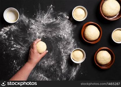 Above view with woman&rsquo;s hand shaping the dough. Making round bread buns in ceramic trays