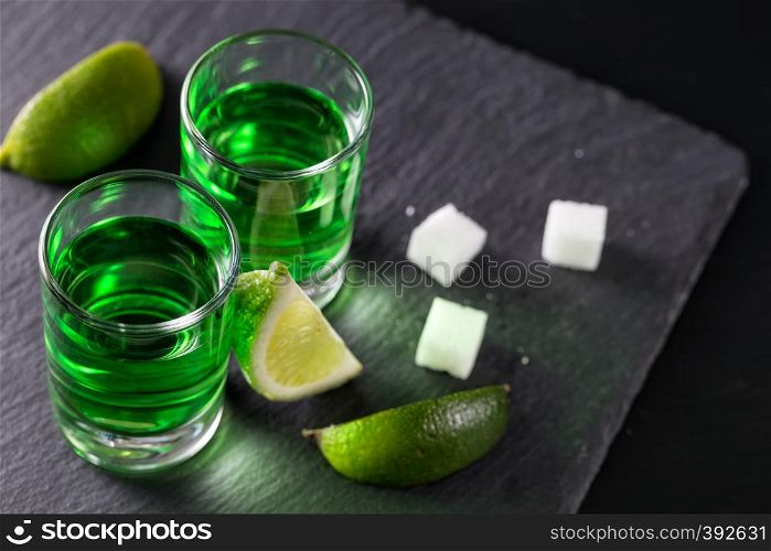 Absinthe with lime slices and sugar pieces on a dark background. Absinthe with lime slices and sugar pieces