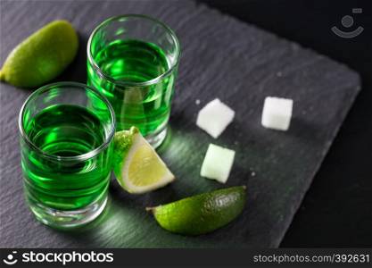 Absinthe with lime slices and sugar pieces on a dark background. Absinthe with lime slices and sugar pieces
