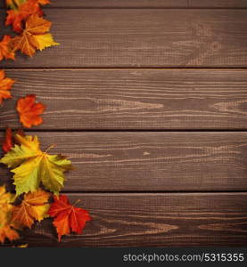 Abstract autumnal backgrounds. Fall maple leaves over vintage wooden desk