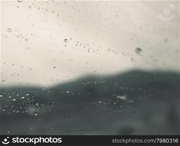 Abstract background of rain drops on glass window with moody tone&#xA;