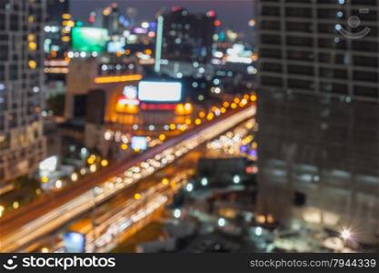 Abstract background of the night light trails with the modern building and traffic on highway, shallow depth of focus