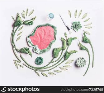 Abstract beauty composing with green tropical leaves and flowers and bowl with sea salt on white table background, top view, flat lay. Natural skin care, spa and cosmetic concept