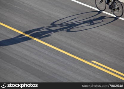 abstract bicyclist shadow on an asphalt highway with yellow line