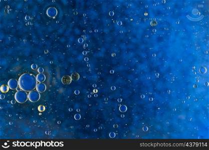 abstract blue background with oil bubbles floating water surface