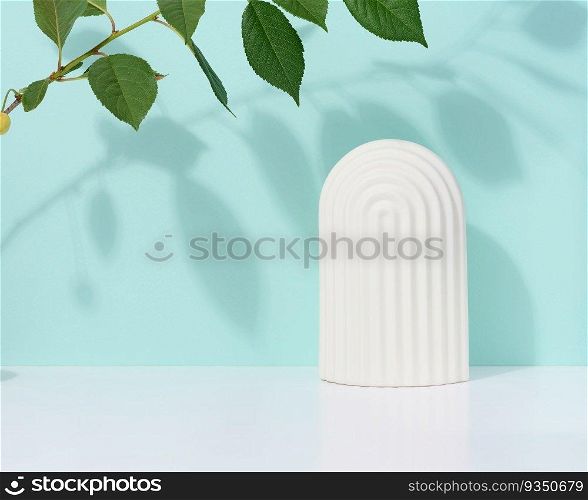 Abstract blue background with white decorative arch and green leaf and shadow, stage for showcasing products, cosmetics