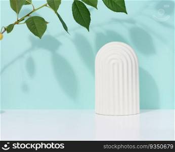 Abstract blue background with white decorative arch and green leaf and shadow, stage for showcasing products, cosmetics