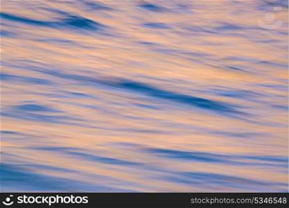 Abstract blur background of sunrise reflecting in ocean waves