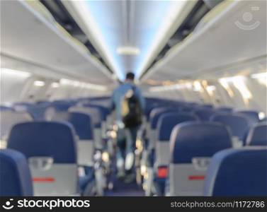 Abstract blurred aircraft cabin view of economy class with passenger background. Travel concept with public aviation transport.