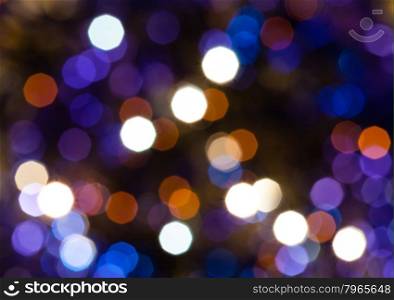 abstract blurred background - dark blue and violet shimmering Christmas lights bokeh of electric garlands on Xmas tree