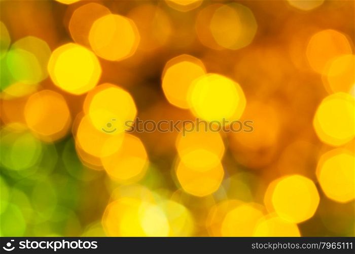abstract blurred background - dark yellow and green shimmering Christmas lights bokeh of electric garlands on Xmas tree