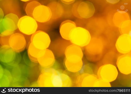abstract blurred background - dark yellow and green shimmering Christmas lights bokeh of electric garlands on Xmas tree