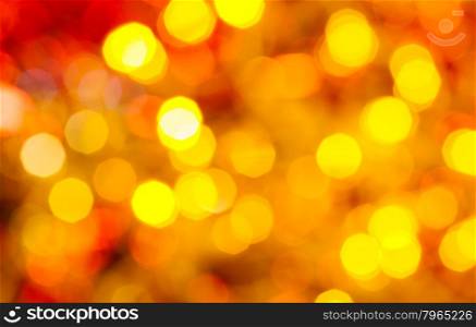 abstract blurred background - dark yellow and red twinkling Christmas lights bokeh of electric garlands on Xmas tree