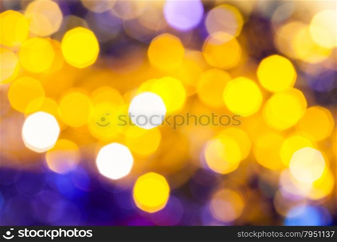 abstract blurred background - dark yellow and violet flickering Christmas lights of electric garlands on Xmas tree