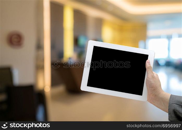 Abstract Blurred background of hotel lobby with hand hold digital tablet. Hotel Blurred background