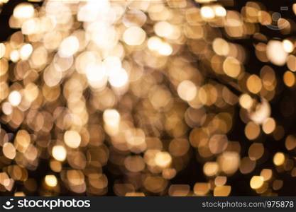 Abstract blurred background with numerous bright gold festive bokeh. Texture with copy space for text. Celebration, holidays concept. Horizontal.
