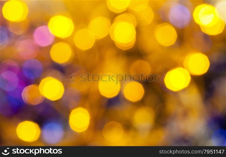 abstract blurred background - yellow and blue shimmering Christmas lights of electric garlands on Xmas tree