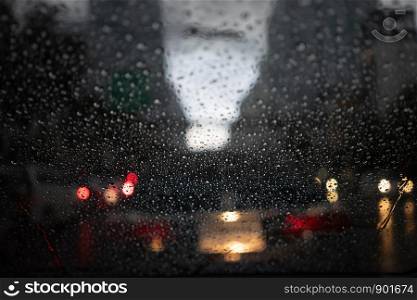 Abstract blurred Rain while the car is in the middle of the road at night Car tail light reflecting with rain drops on the car mirror