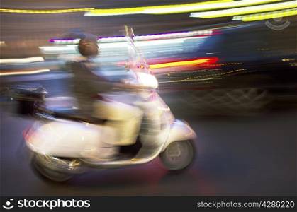 Abstract blurry image of a scooter driving at night.