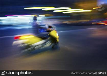 Abstract blurry image of a scooter driving at night.