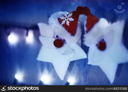 Abstract Christmas background, little white stars with Santa Claus face hanging on glowing blue wall, New Year decoration, beautiful winter holiday ornament