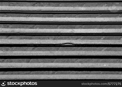 Abstract close up photo of roof tiles stacked one on top of the other. Only horziontal lines of gray are visible.