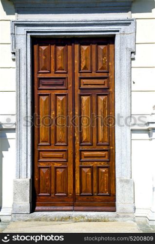 abstract cross brass brown knocker in a closed wood door varese italy azzatesumirago sunny day