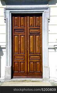 abstract cross brass brown knocker in a closed wood door varese italy azzatesumirago sunny day