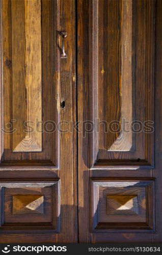 abstract cross brass brown knocker in a closed wood door varese italy sumirago sunny day
