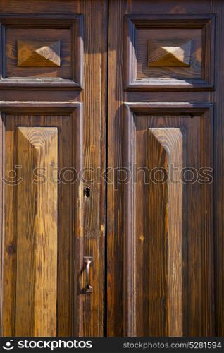 abstract cross brass brown knocker in a closed wood door varese italy sumirago sunny day