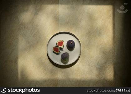 Abstract Figs fruits placed on a plate on a table with a natural frame from sun