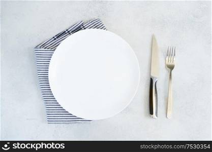 Abstract food background - empty white plate with blue napkin and cutlery. Abstract food background