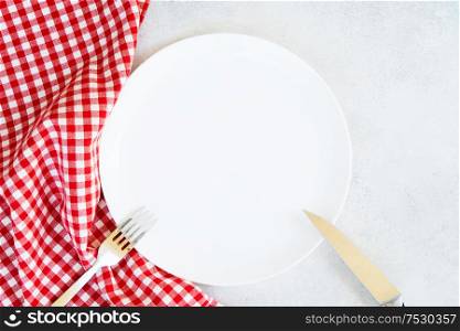 Abstract food background - empty white plate with red and white napkin and cutlery. Abstract food background